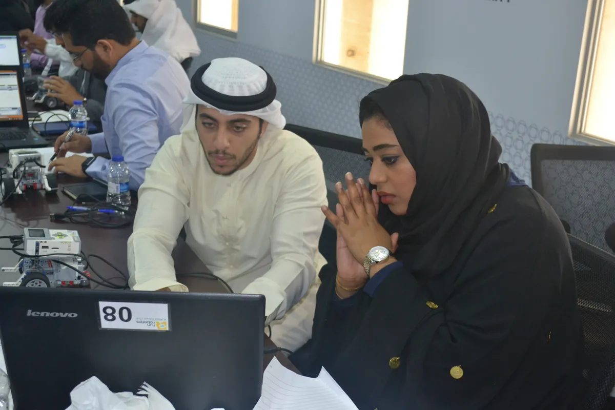 Two Dubai Financial Market employees program a robot on a laptop during an innovation workshop