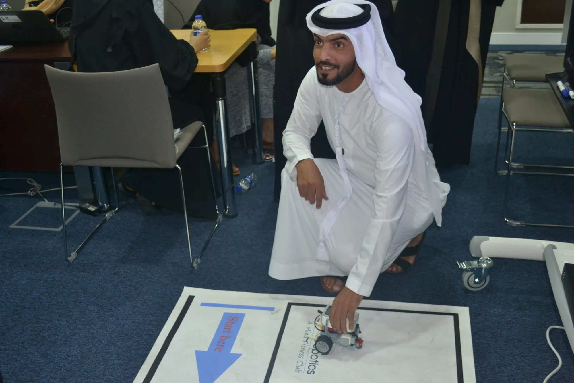 A Dubai Financial Market employee sets a robot on the start line of a challenge mat during an innovation workshop