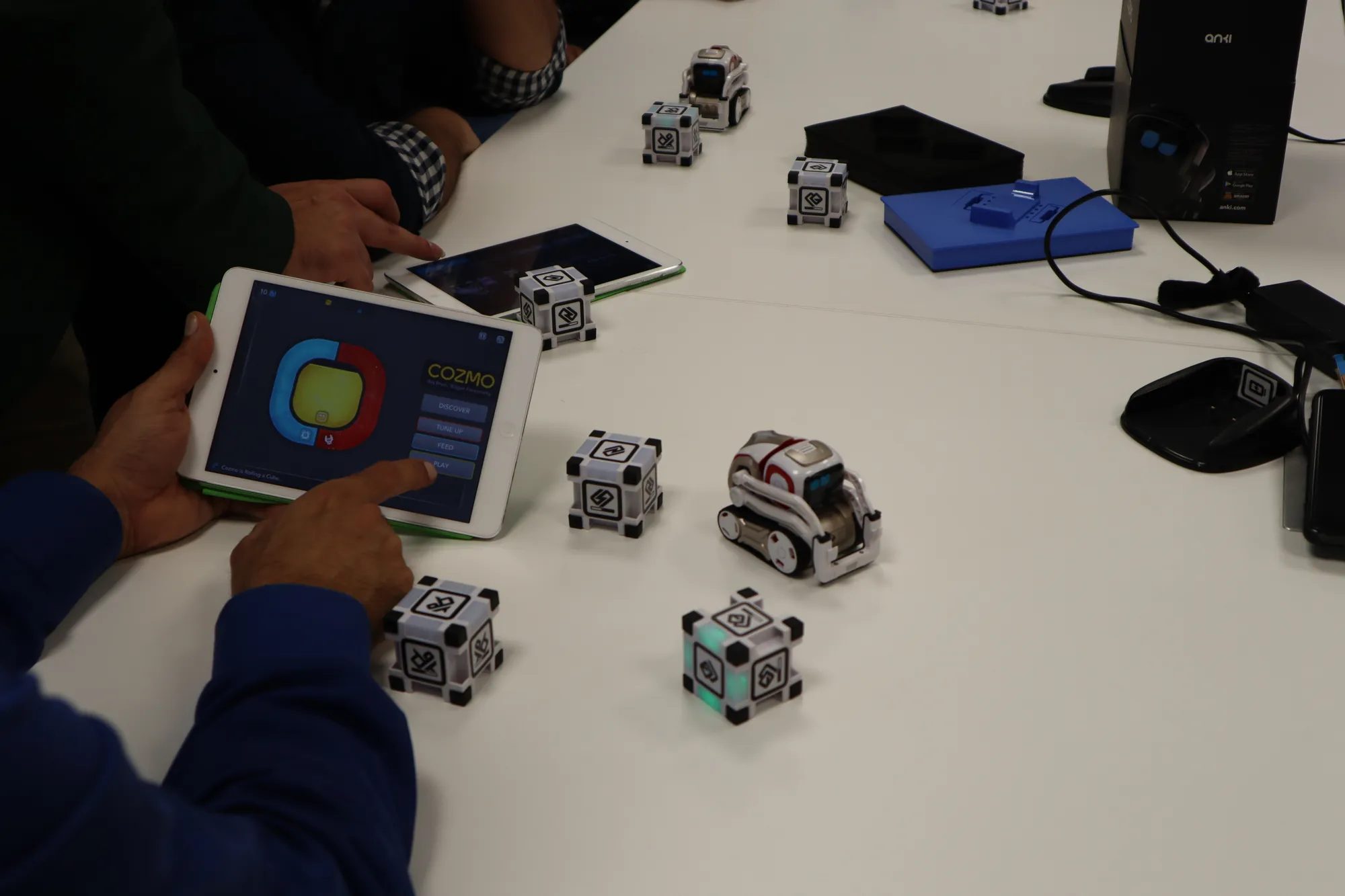 Colleagues code small robots on tablets during a robotics team building workshop