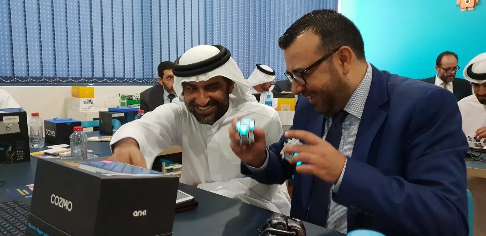 Government staff in kandura and suits test small robots together during a hands-on AI workshop for employees