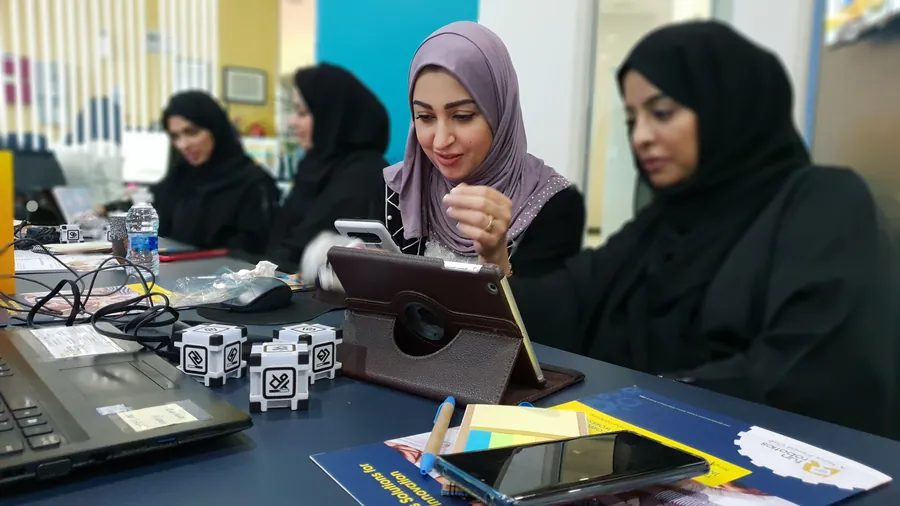 Securities and Commodities Authority staff code small robots on tablets during an AI workshop for employees