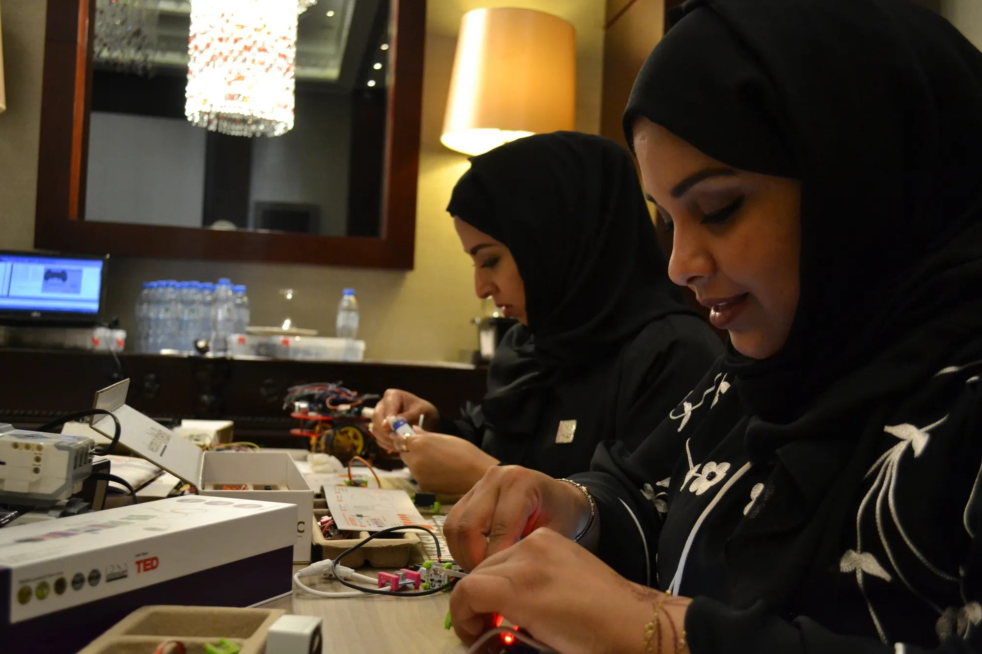 Two participants wire electronic modules at a makerspace table during an IoT workshop