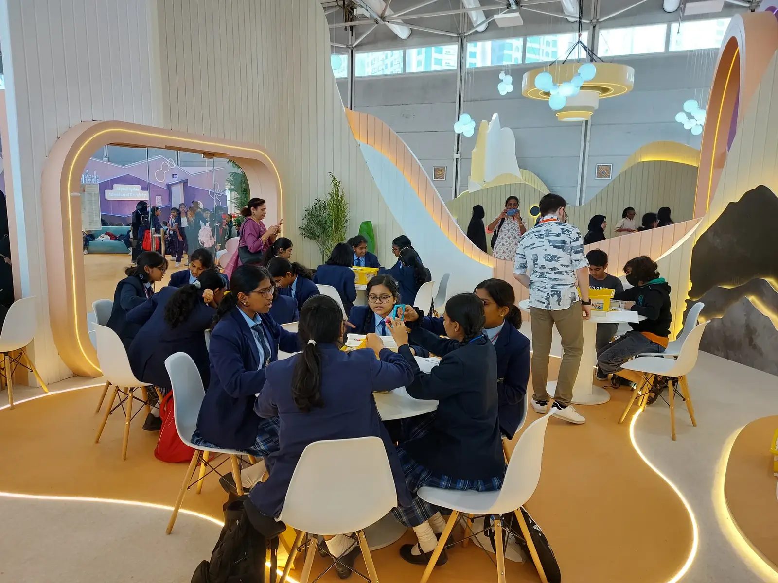 School groups build robots at tables inside a book fair pavilion during a kids' robotics activation