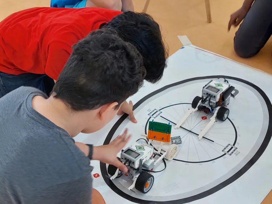 Two boys guide robots around a sumo ring during a robot sumo workshop at a book fair